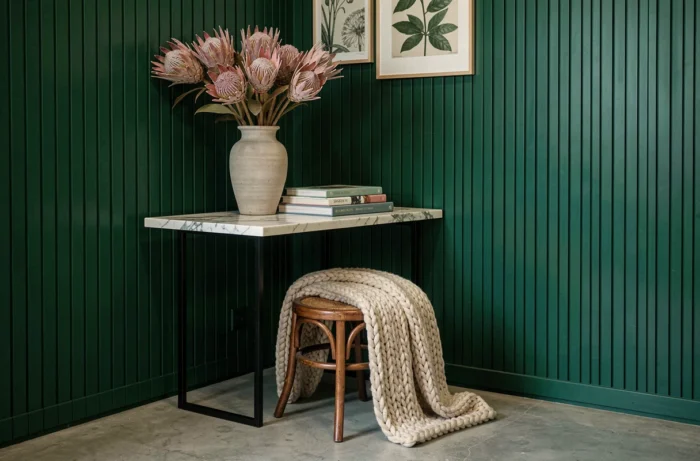 Console marbre et vase en céramique sur fond de mur vert cannelé, tendances décoration intérieur 2024